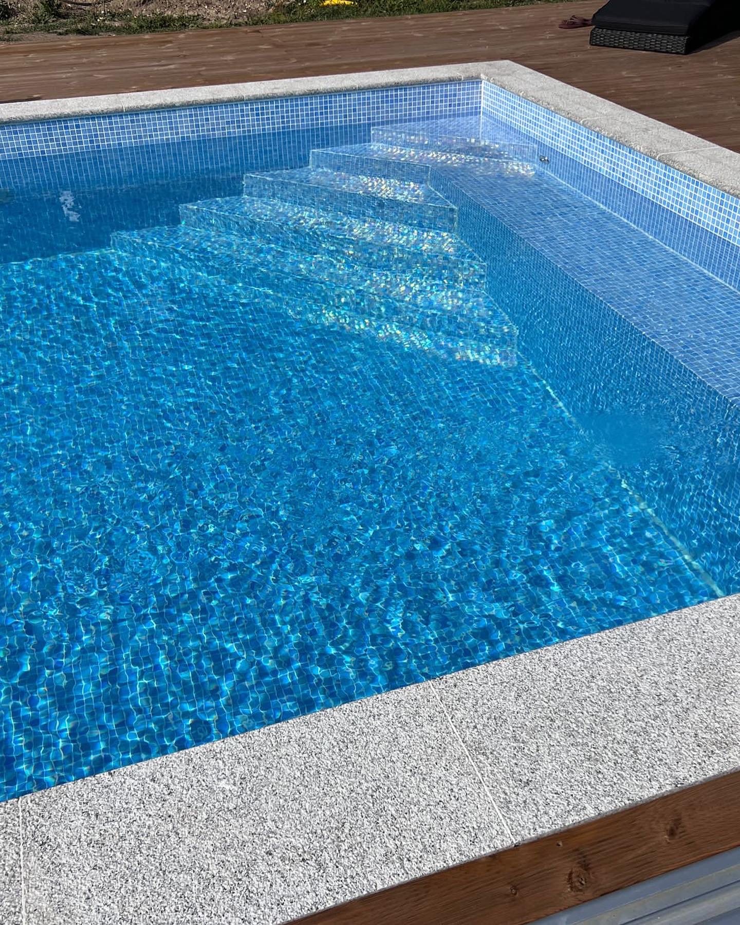 Privat pool med blått mosaikarbete och trall runt bassängen